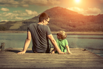 Happiness father and son on the pier at sunny day under sunlight