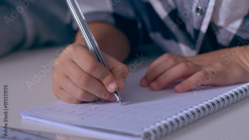 Hands of prescooler learning to write numbers in copybook photo