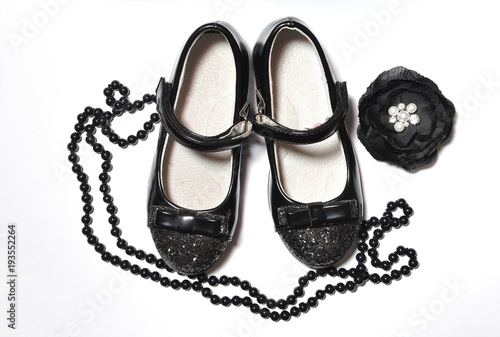 Beautiful accessories in black for girls. Shoes, beads and brooch on a white background