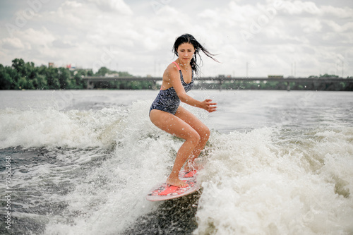 Woman riding board on wave of motorboat