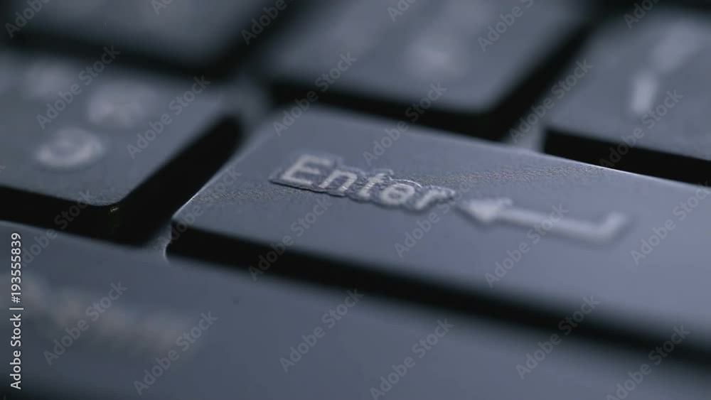 Macro view of black keyboard with enter key and finger pressing it Macro view of black keyboard with enter key and finger pressing it