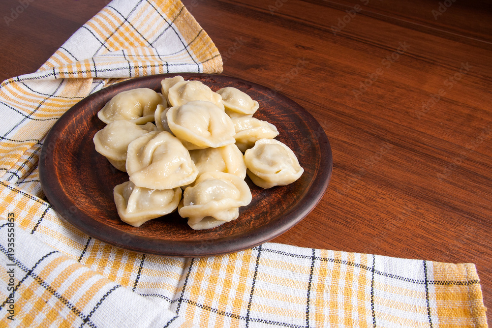 Boiled Ukrainian meat dumplings or ravioli on wooden background.