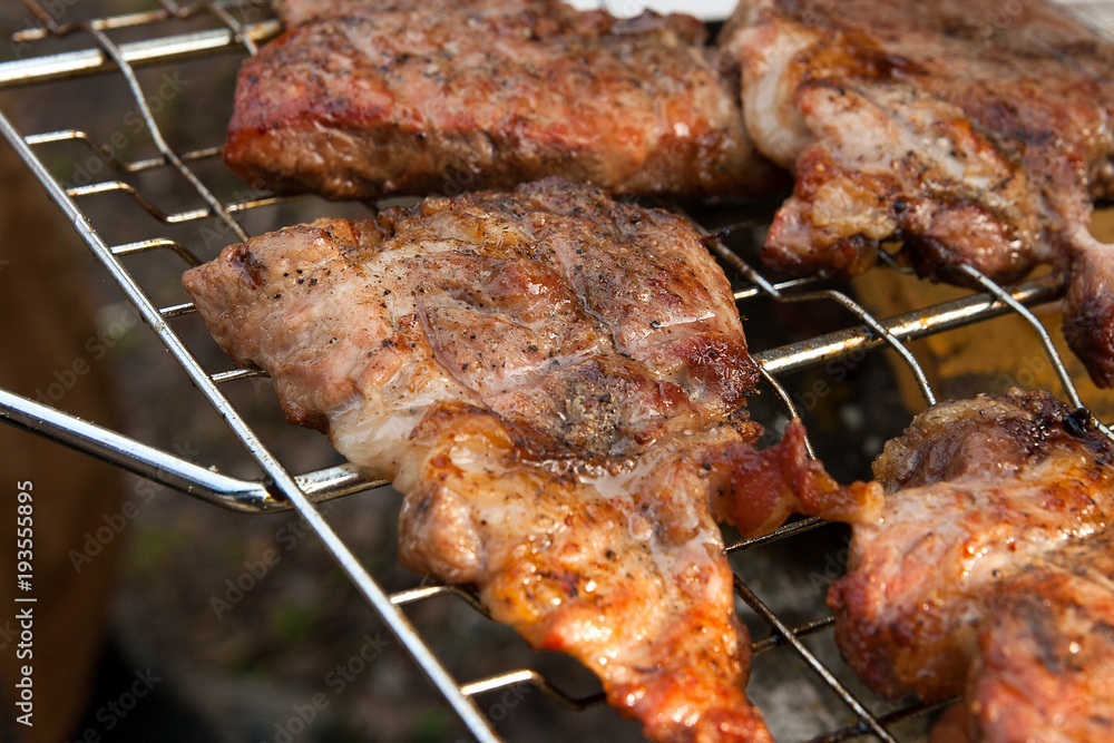 Close up view of juicy pork steak cooked on an open flame grill..