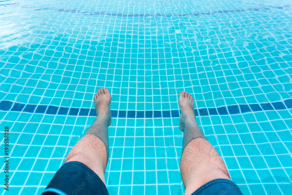 A man put his legs in pool for relax.