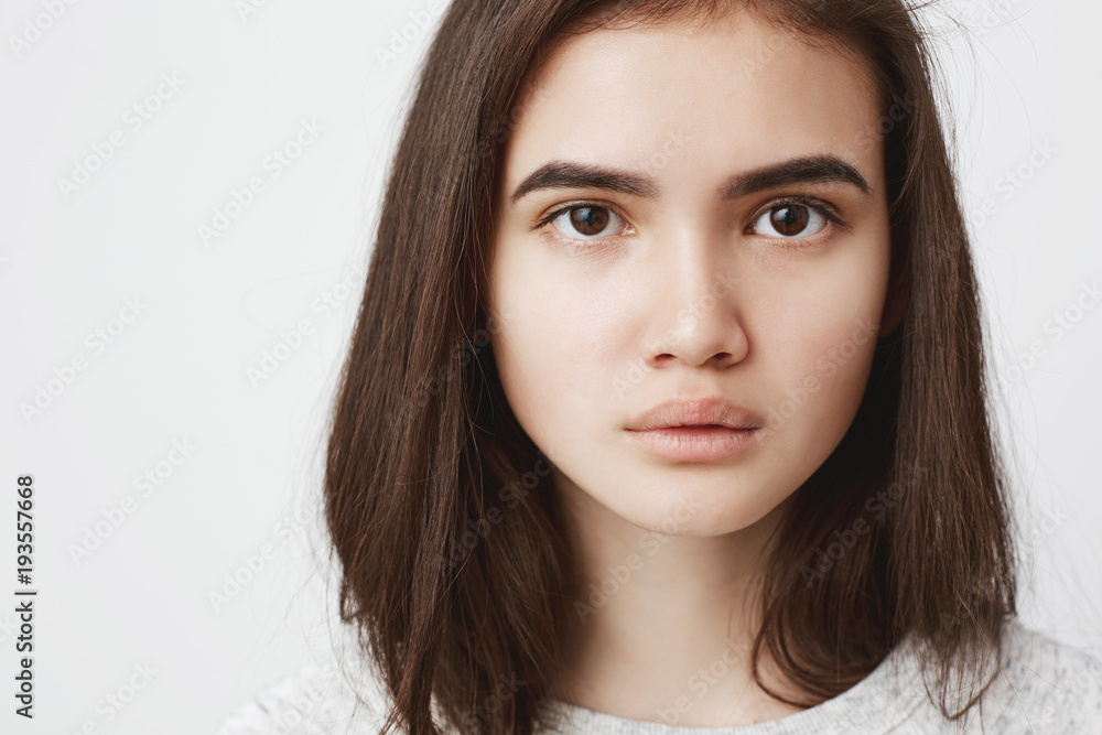 Close up portrait of cute teenage girl with serious and concentrated expression, over white background. Attractive female is having serious convo with is about to tell her truth.