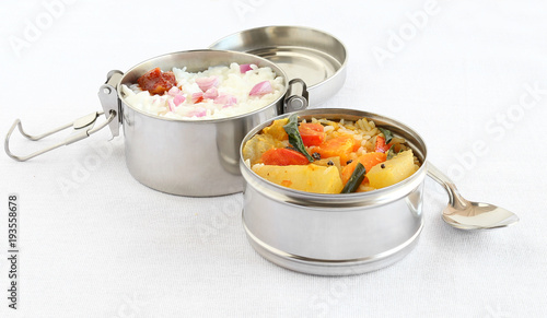 Healthy south Indian vegetarian lunch in two boxes of a lunchbox, with rice and sambar, a semi-liquid food made from lentils and vegetables, in one box, and curd rice in another box.