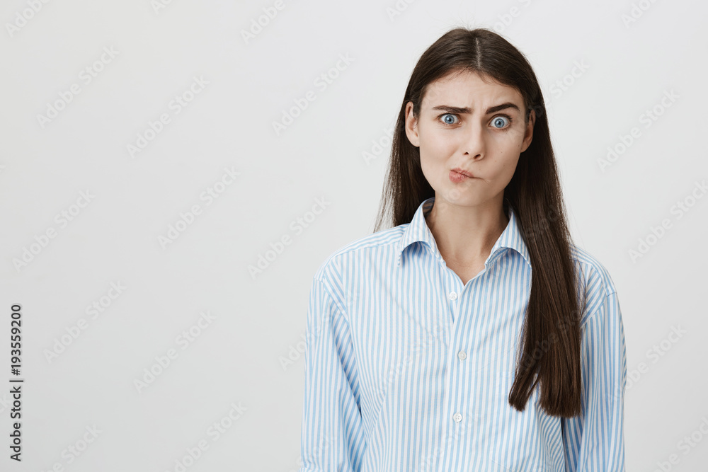 Perplexed and confused woman with questioned expression standing over gray background having no clue what to do next. Foreigner asking her something but she can not understand his language Perplexed and confused woman with questioned expression standing over gray background having no clue what to do next. Foreigner asking her something but she can not understand his language