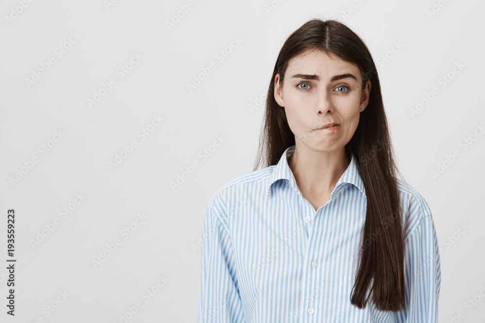 Portrait of european woman with perplexed and gloomy epxresion standing over gray background in blue-collar shirt. Wife weighing options while thinking about bills and from who she can loan Portrait of european woman with perplexed and gloomy epxresion standing over gray background in blue-collar shirt. Wife weighing options while thinking about bills and from who she can loan