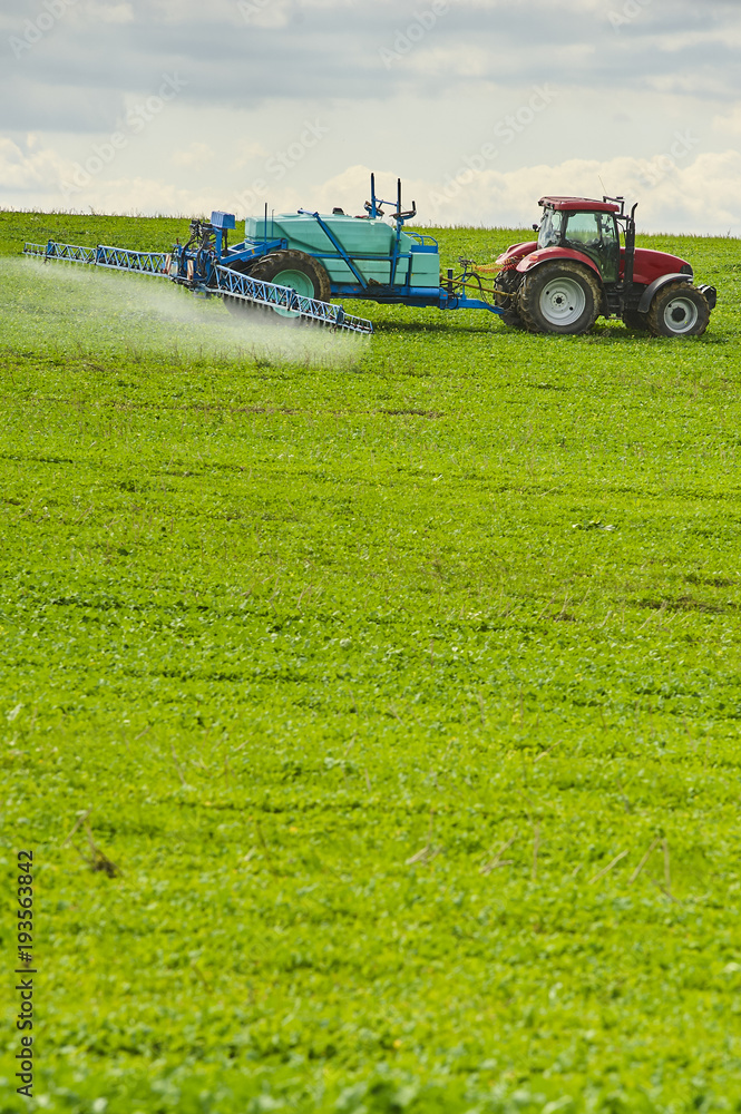 Tractor spraying pesticides on field with sprayer at spring Tractor spraying pesticides on field with sprayer at spring