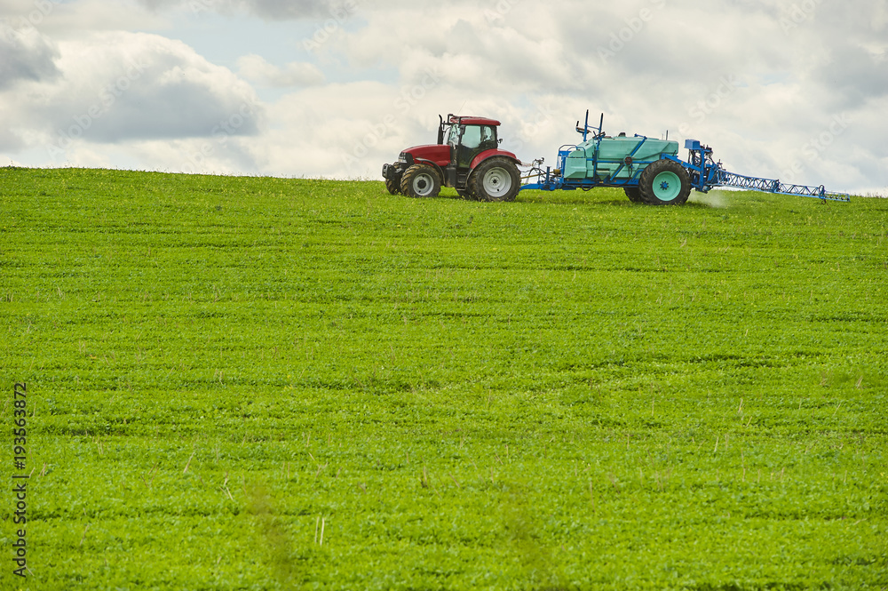 Tractor spraying pesticides on field with sprayer at spring Tractor spraying pesticides on field with sprayer at spring