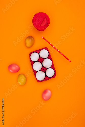 top view of chicken eggs in red egg tray and coffee isolated on orange