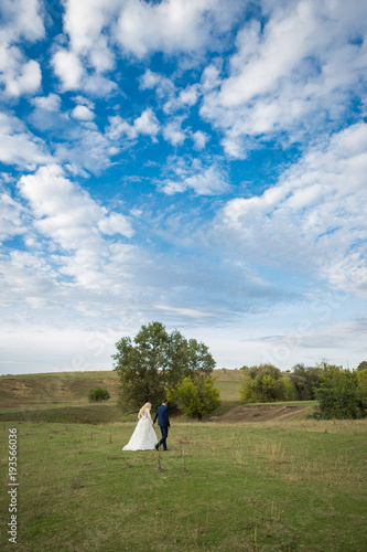 The newlyweds in the background of beautiful clouds