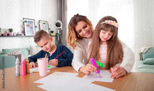 Happy loving family, mother with children together paint at home