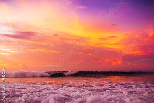 Waves in ocean and bright pink sunset or sunrise. Ocean with warm sunset colors