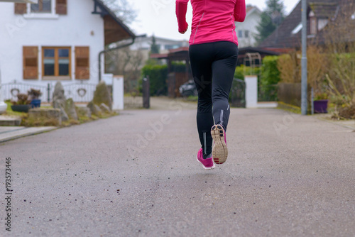 Fototapeta Naklejka Na Ścianę i Meble -  Cropped rear view of an athletic woman jogging