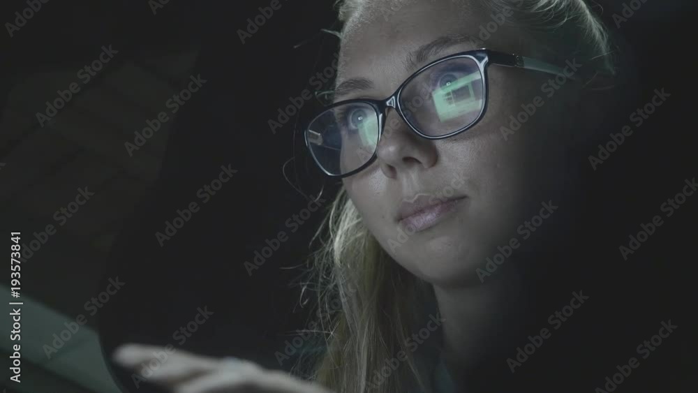 Hipster student girl browsing the internet,looking at monitor of modern laptop,closeup shot of screen reflection in glasses.Attractive young businesswoman working at night via computer at office