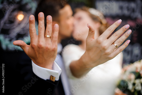 Bridegroom and bride kissing and showing wedding rings on their fingers