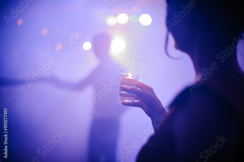 Back view of woman drinking shot in night club