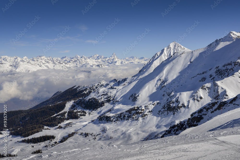 Panoramic view of wide and groomed ski piste in resort of Pila in Valle d'Aosta, Italy during winter