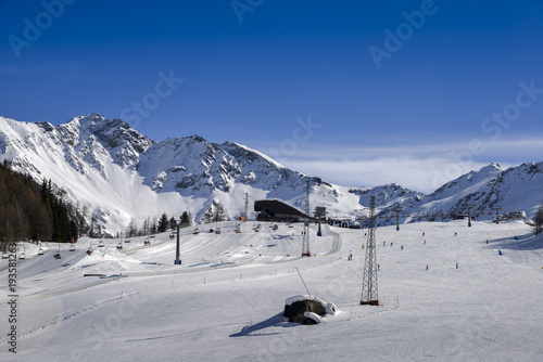 Unidentifiable skiers at ski resort in Pila, Valle d'Aosta, Italy with chairlift and mountain backdrop and copy space