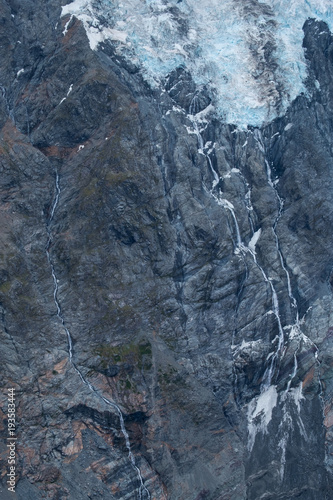 Black tall cliff with ice and waterfall begining of the glacier in Mt Cook National Park.