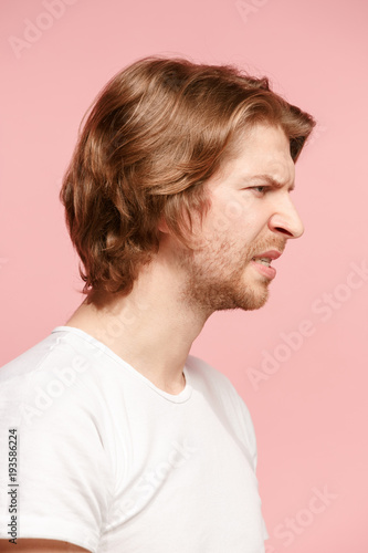Young man with disgusted expression repulsing something, isolated on the pink
