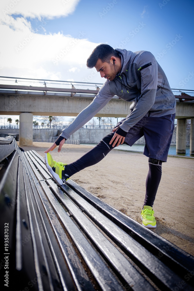 Young athlete man stretching after running in a park