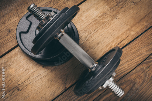 iron dumbbell on a wooden plank with copy space