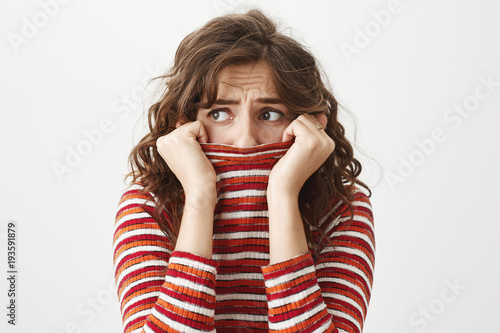 Foto Indoor shot of good-looking caucasian woman hiding in sweater and looking aside