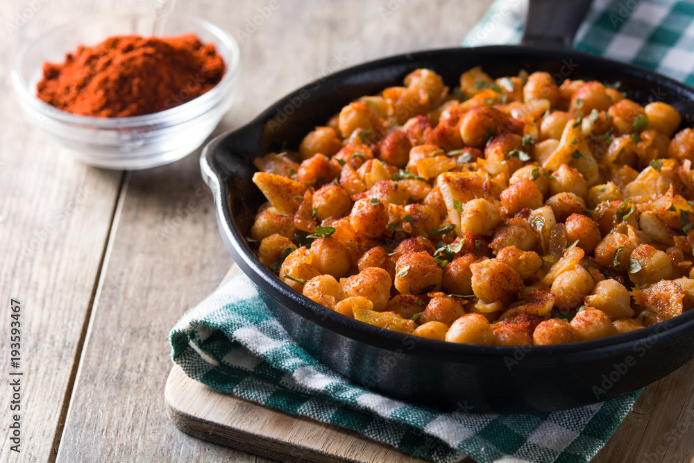 Fried spicy chickpeas in frying pan on wooden table Fried spicy chickpeas in frying pan on wooden table