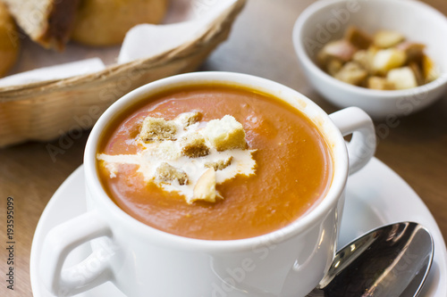 Tomato puree soup with cream and crackers in a white plate on the table