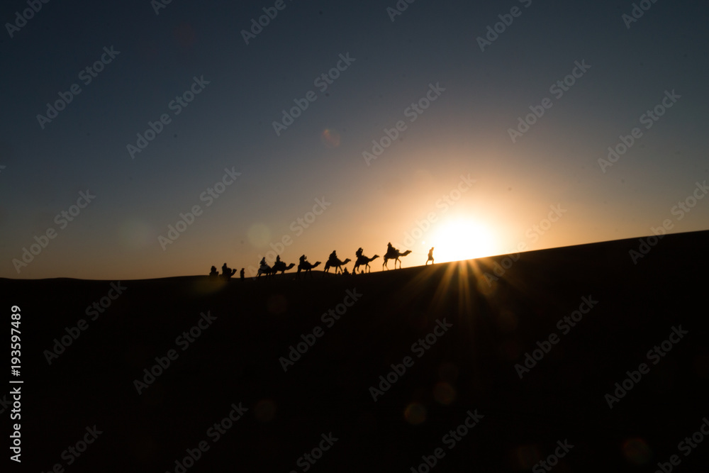 People on camels silhouettes in the sahara in Morocco