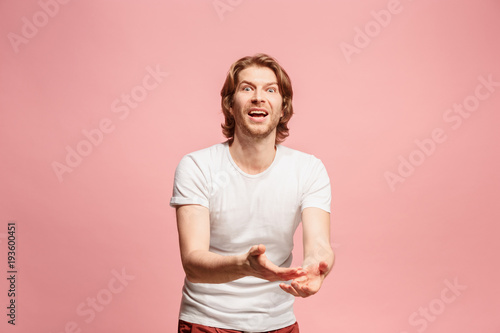 Beautiful male half-length portrait isolated on pink studio backgroud. The young emotional surprised man