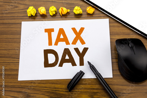 Conceptual hand writing text showing Tax Day. Business concept for Income taxation Refund written on sticky note paper on the wooden background with marker mouse and tablet office view. photo