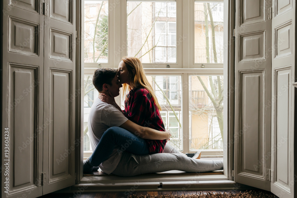 Couple kissing on window sill Couple kissing on window sill