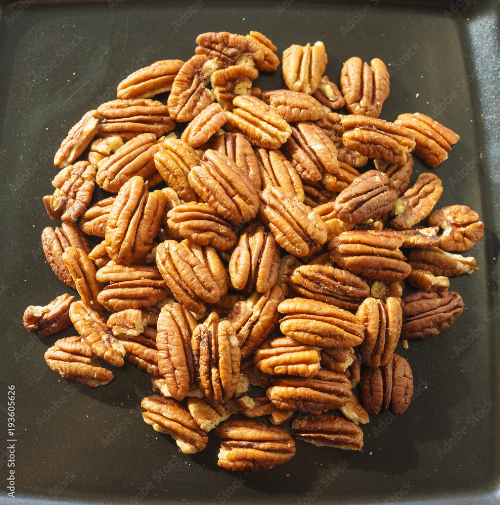 A bunch of nuts pecan on a black plate. Close-up photo A bunch of nuts pecan on a black plate. Close-up photo