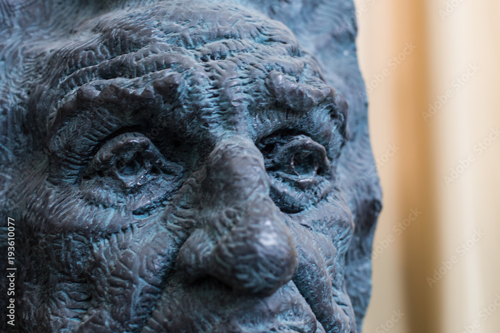 Close up of a face dark painted statue with blue details of an old man