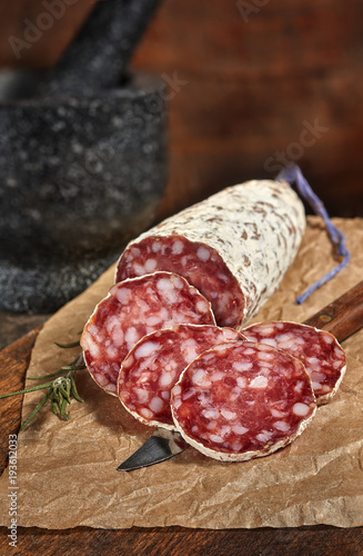 Salami slices on the wooden table. Spicy and tasty.