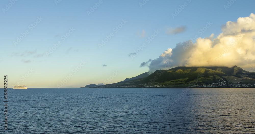 Cruise ship floating off the coast of St Kitts as sunlight hits the mountains.