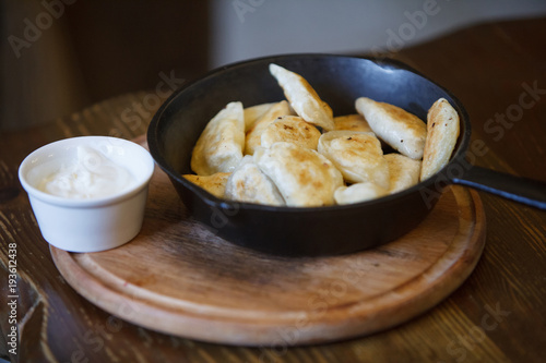 Pan-fried Vareniks in a frying pan. Sour Cream. Delicious lunch