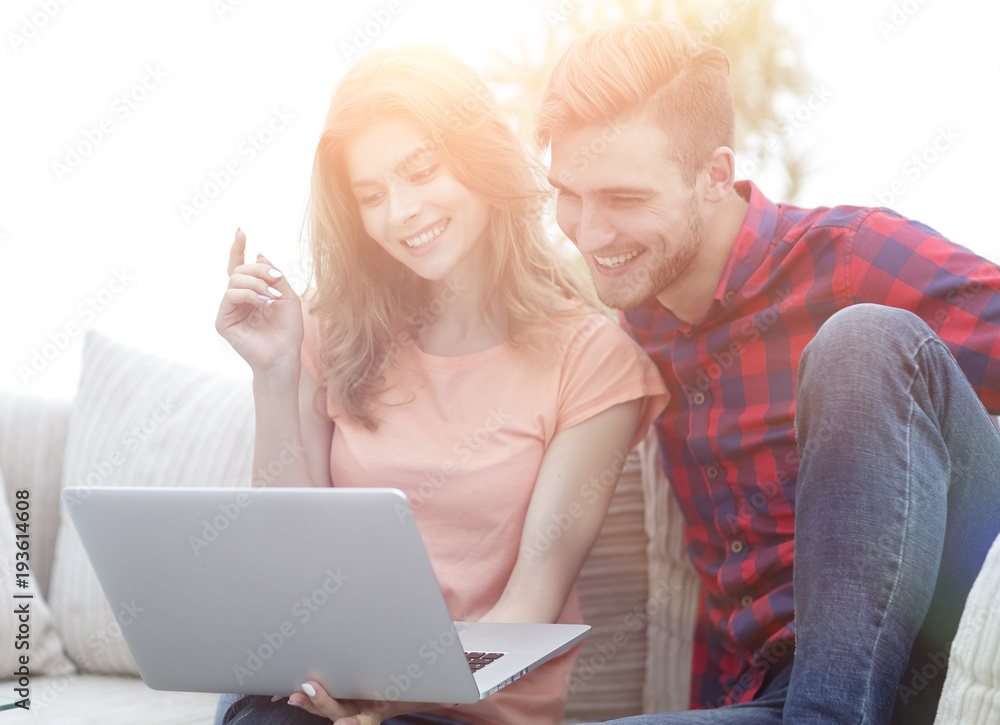 young man with his girlfriend watching a TV show on the laptop sitting in the living room young man with his girlfriend watching a TV show on the laptop sitting in the living room