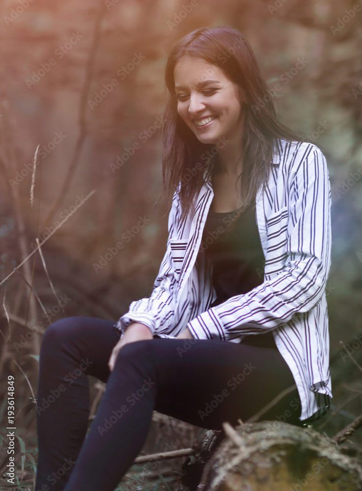Obraz premium young woman sitting on a log in the woods.