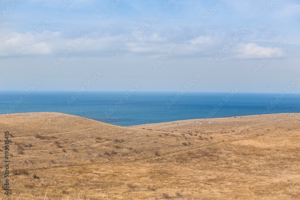 Hilly seashore and a blue surface of the sea.