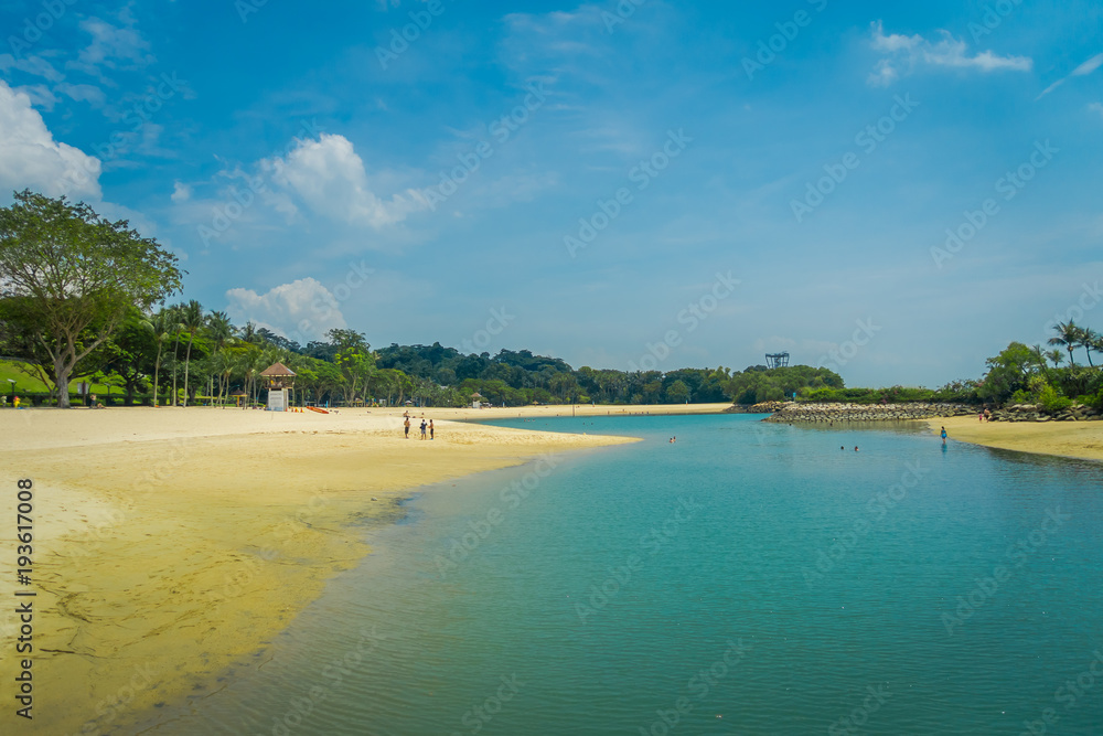 Beautiful outdoor view of unidentified people enjoying the yellow sand and tropical beach in sentosa and swimming in a natural pool in Singapore Beautiful outdoor view of unidentified people enjoying the yellow sand and tropical beach in sentosa and swimming in a natural pool in Singapore