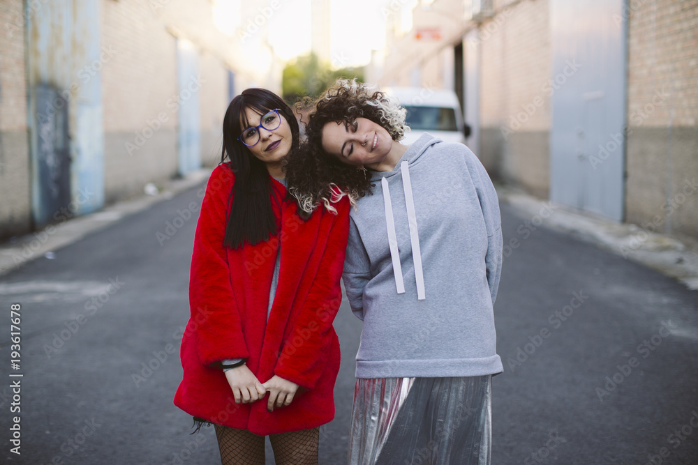 Close-up portrait of two young women wearing a modern look in an urban background.