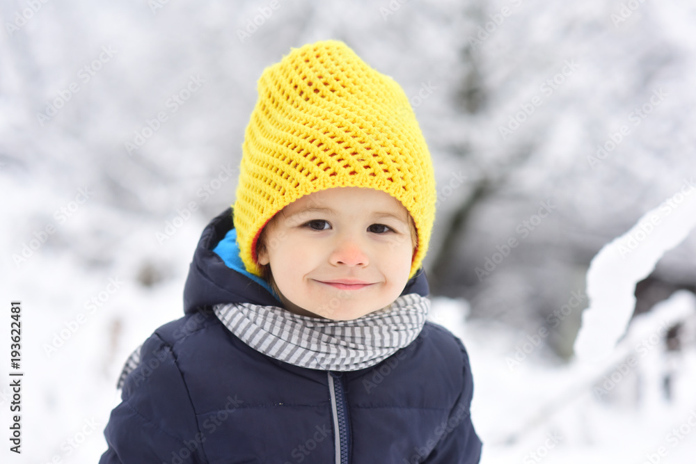Cheerful kid smiling in winter snow park. Portrait of happy joyful beautiful little boy on white background of snowing trees. Happy childhood on walk, child smile to camera. Beautiful child portrait Cheerful kid smiling in winter snow park. Portrait of happy joyful beautiful little boy on white background of snowing trees. Happy childhood on walk, child smile to camera. Beautiful child portrait