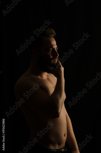 shirtless, handsome young man standing. Studio shot of light,
