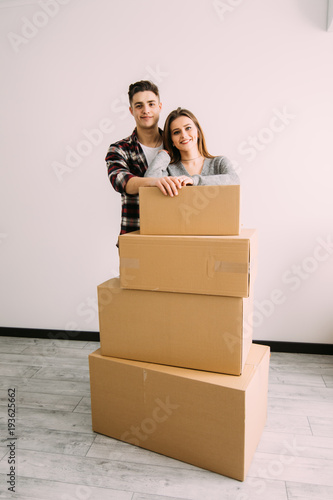 Young happy couple with boxes in apartment after moving in new apparment