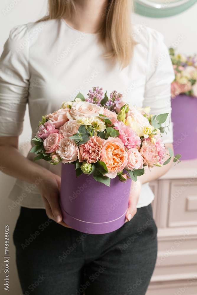 Selective focus on bouquet in lilac hatbox. beautiful luxury bunch of mixed flowers in womans hand. the work of the florist at a flower shop. perfect gift or compliment. Selective focus on bouquet in lilac hatbox. beautiful luxury bunch of mixed flowers in womans hand. the work of the florist at a flower shop. perfect gift or compliment.