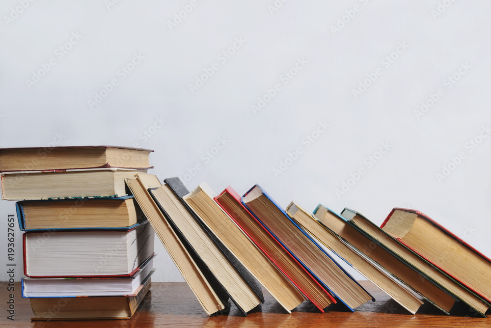 Stack of different books on a table against a white wall background Stack of different books on a table against a white wall background